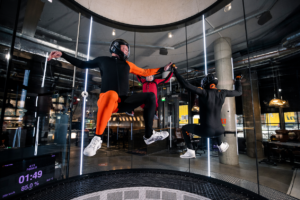 A group of people experiencing the thrill of freefall in the Fööni vertical wind tunnel, showcasing high-energy indoor skydiving.